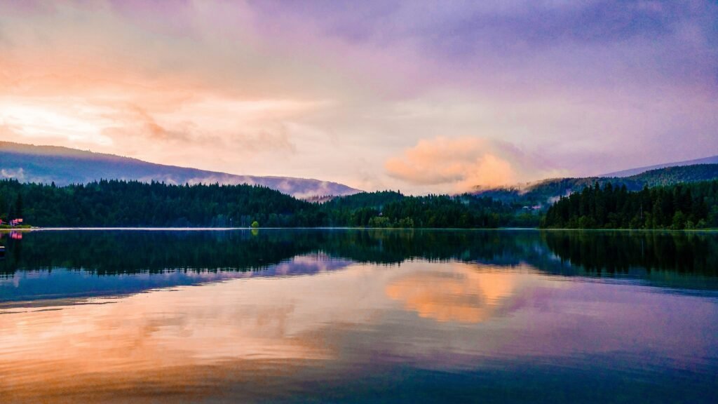 Vibrant sunset over a tranquil lake with mountain reflections in Clearwater, BC.